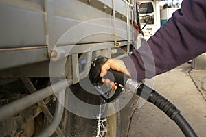 man filling up his 4WD car with fuel from a black petrol bowser, rural New South Wales