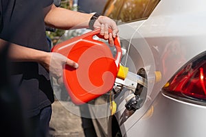 Man fills the fuel into the gas tank of car from a red canister or plastic fuel cann .maintenance repair car concept ,selective