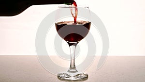 Man fills transparent glass with red wine in restaurant indoor.