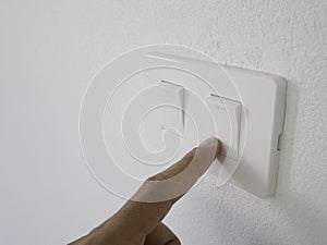 Man finger press white switch off light on white wall