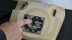 Man finger pressing numbers buttons on classic retro phone telephone