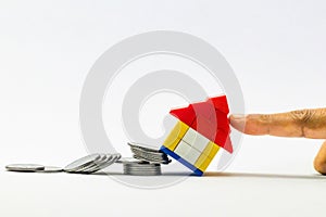 Man finger supporting a falling house from column of coins in home insurance concept