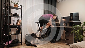 Man is finishing online bicycle race on stationary bike trainer. Indoor cycling. Cyclist finishes online cycling competition on sm