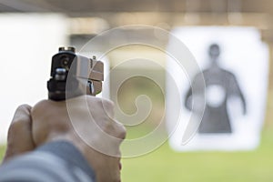 Man Firing Pistol at Target in Shooting Range