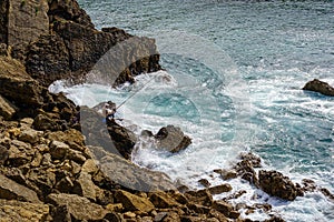 Man fished on the rock cliffs with strong waves of the sea. Santander