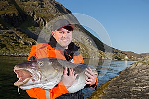 Man fisherman holding a fish ogromnyu Cod. Smiling