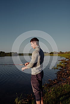 A man fisherman on the river bank catches a fish