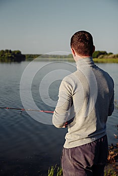 A man fisherman on the river bank catches a fish