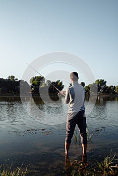 A man fisherman on the river bank catches a fish