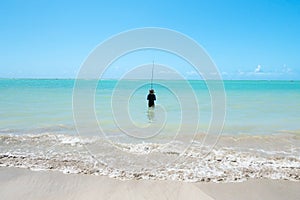 Man fishing alone on the beautiful beach of Barra Grande, at Maragogi - AL, Brazil photo