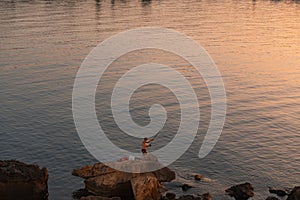 a man fishing on the beach at sunset