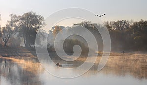 Man fishing on a boat in a mystic foggy lake
