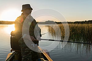 A man is fishing from a boat on sunset