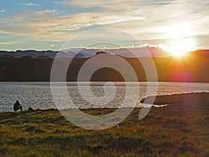 Man fishing on Iceland lake Thveit near Hofn on sunset with snow