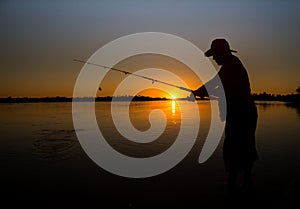 Man fishing on a lake from the boat at sunset