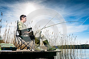 Man fishing at lake sitting on jetty