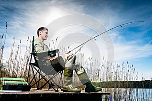 Man fishing at lake sitting on jetty