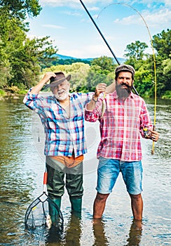 Man fishing. Men fishing in river during summer day. Father and son fishing. Fly rod and reel with a brown trout from a