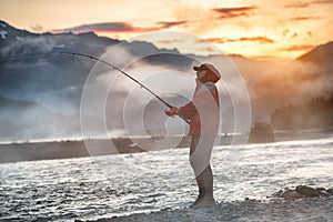 Man fishing at morning sunrise in a mountain river in Alaska, USA.