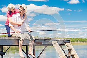 Man with a fishing pole and his beloved woman on a wooden pier o