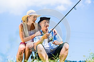 Man with fishing rod angling at lake enjoying hug