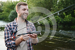 Man with fishing rod, fisherman men in river water outdoor. Catching trout fish in net. Summer fishing hobby