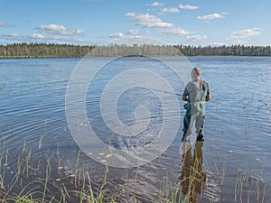 Man fishing with spinning in lake. Ecotourism, visiting fragile, pristine, undisturbed natural