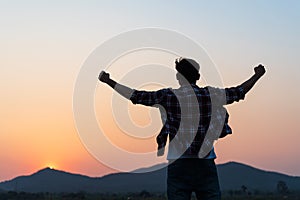 Man with fist in the air during sunset sunrise mountain in background. Stand strong. Feeling motivated, freedom, strength and