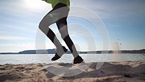 Man in fitness clothing running along sandy beach. Runner athlete feet running on sand. Fitness silhouette sunrise jog, workout