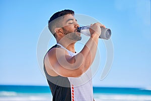 Man, fitness and drinking water on beach in hydration after workout, training or outdoor exercise. Thirsty or sporty