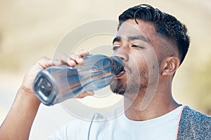 Man, fitness and drinking water in nature for hydration, running exercise or cardio workout outdoors. Thirsty male