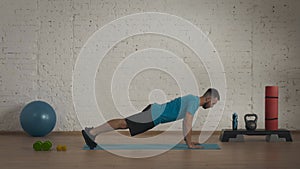 Man fitness instructor in sportswear doing classic push ups exercise for online class at the home studio.