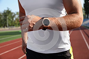 Man with fitness tracker running at stadium