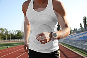 Man with fitness tracker running at stadium, closeup