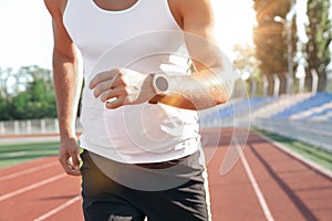 Man with fitness tracker running at stadium, closeup