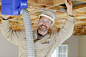 Man fitting cables into junction box in roofspace