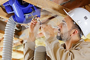 Man fitting cables into junction box in roofspace