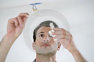 Man fitting light to ceiling