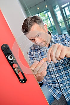 Man fitting lock to internal door