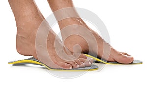 Man fitting orthopedic insoles on white background, closeup. Foot care