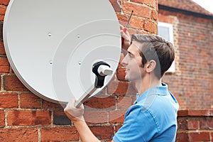 Man Fitting TV Satellite Dish To House Wall