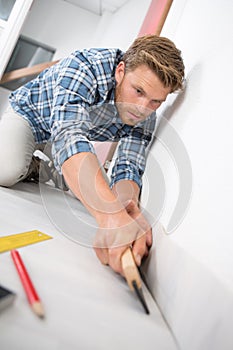 Man fitting underlay against wall