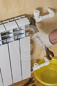 A man fixes a leak of a radiator in a private home. Accident of the heating system of a private house.