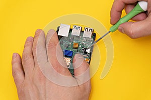 Man fixes microcomputer with screwdriver photo