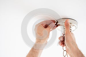 Man fixing ceiling light on white background