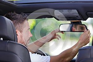 man fixing front mirror in car