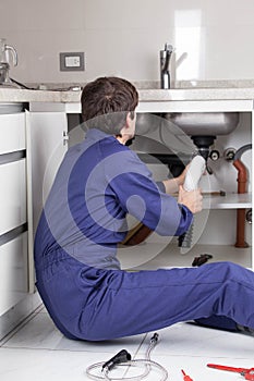 Man fixing a pipe sitting on the floor