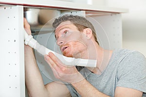 man fixing pipes under sink