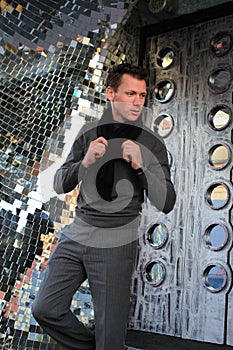 Man fixing scarf near mirror wall