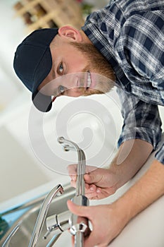 man fixing sink pipe in kitchen